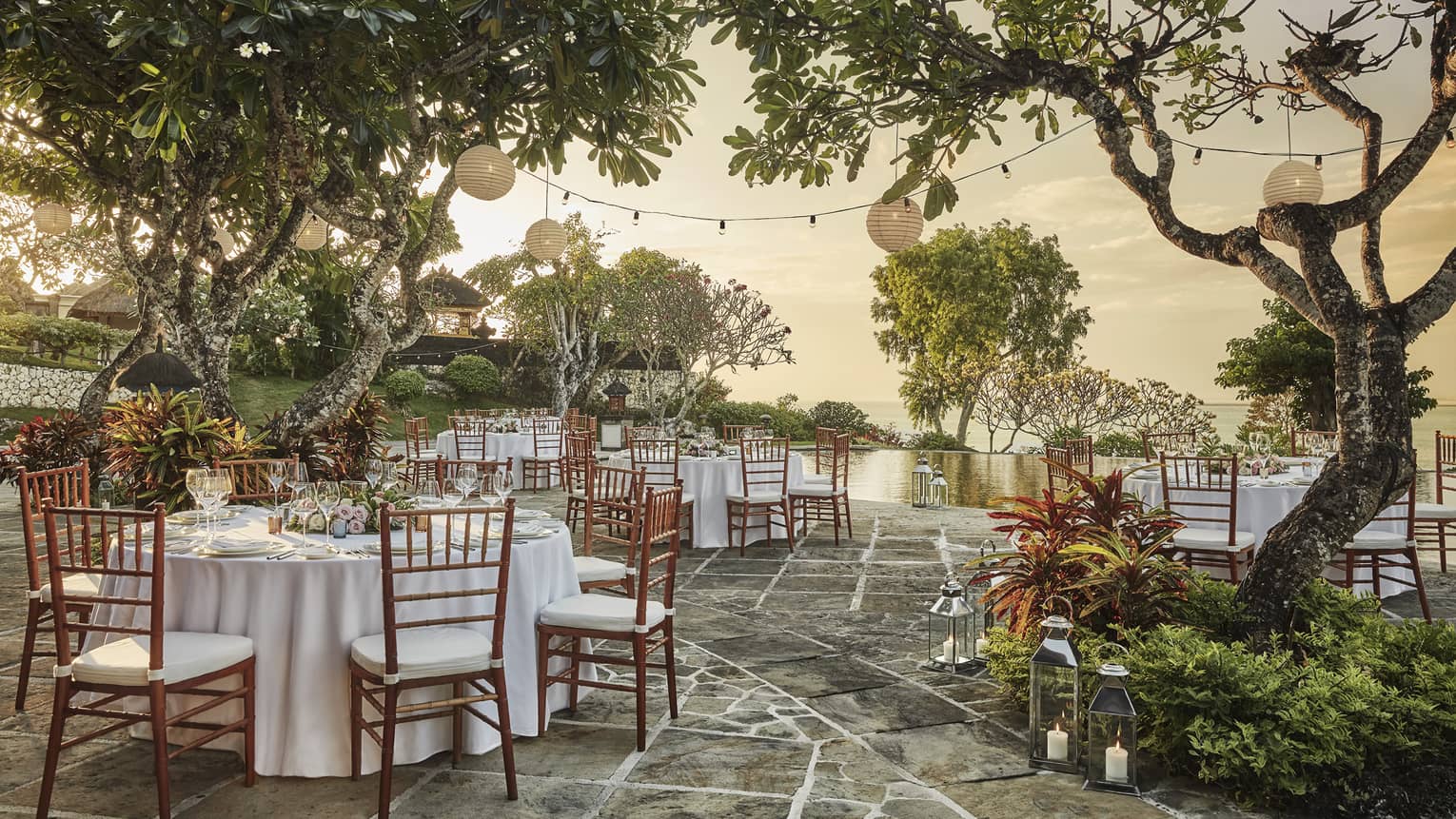 Patio wedding reception at sunset, small round banquet tables and chairs under trees