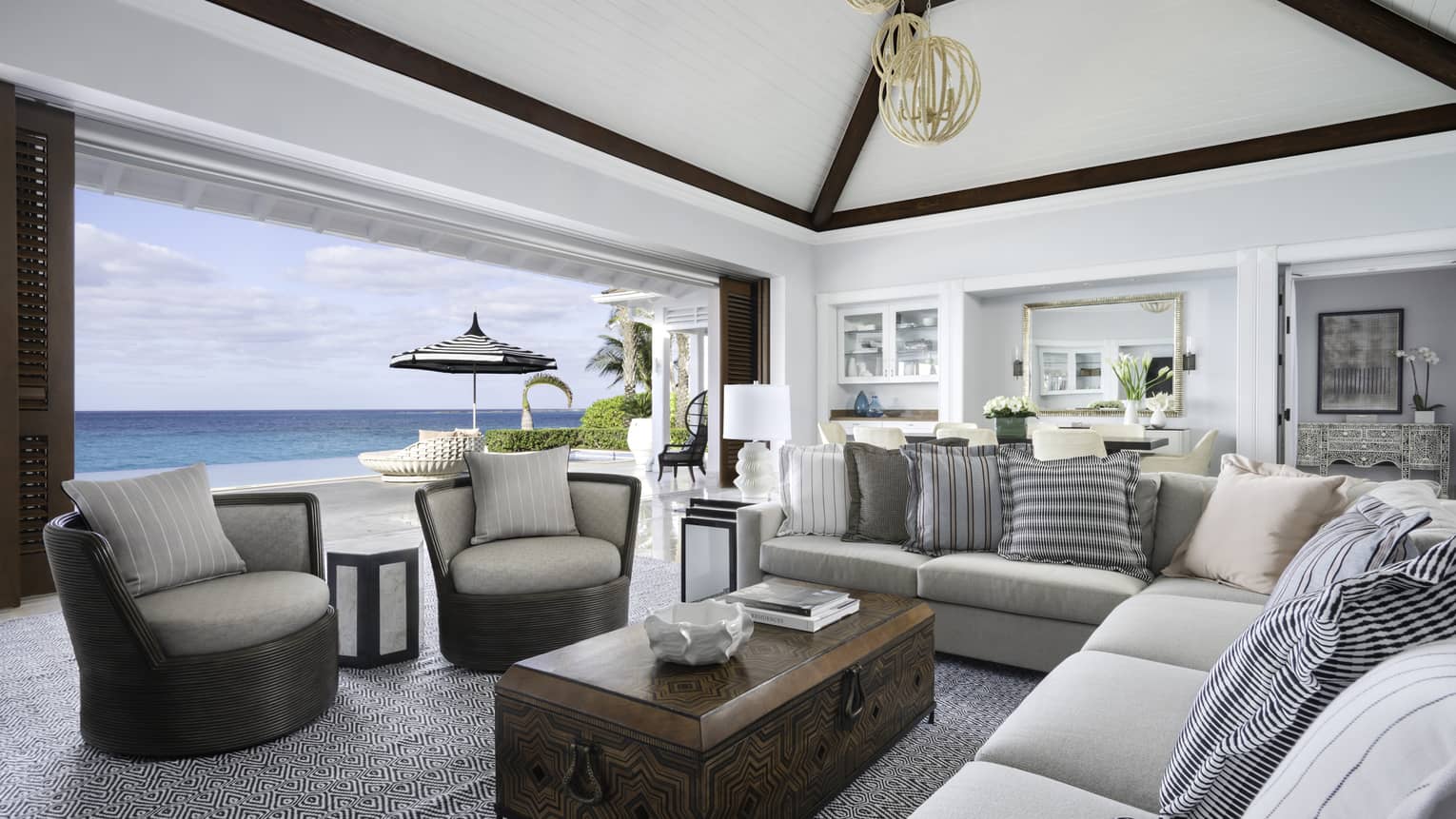 Beachfront Villa Residence large living room with modular sofa, armchairs by open wall to patio overlooking ocean  