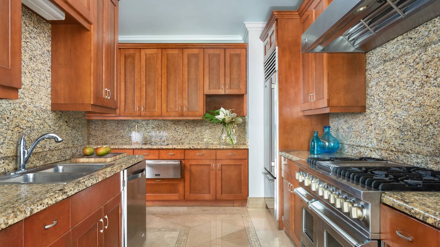 Beachfront Villa Residence Kitchen with wood cabinets, marble counters and backsplash, stainless steel appliances