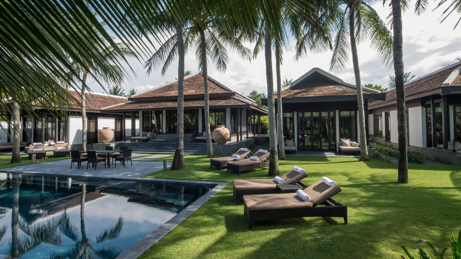 Three-bedroom Hilltop Villas, palm trees, lounge chairs on lawn around outdoor pool