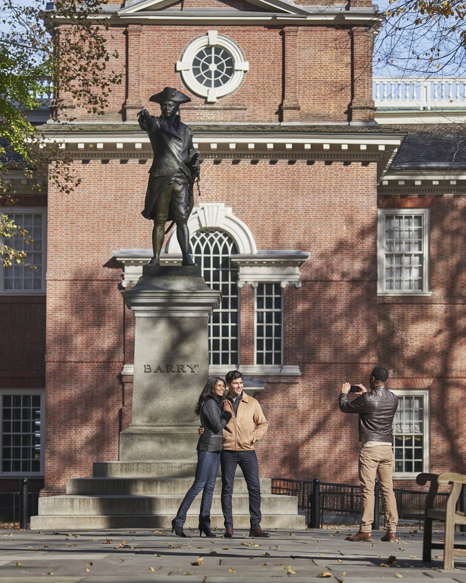 Couple poses for photo in front of statue and historic building