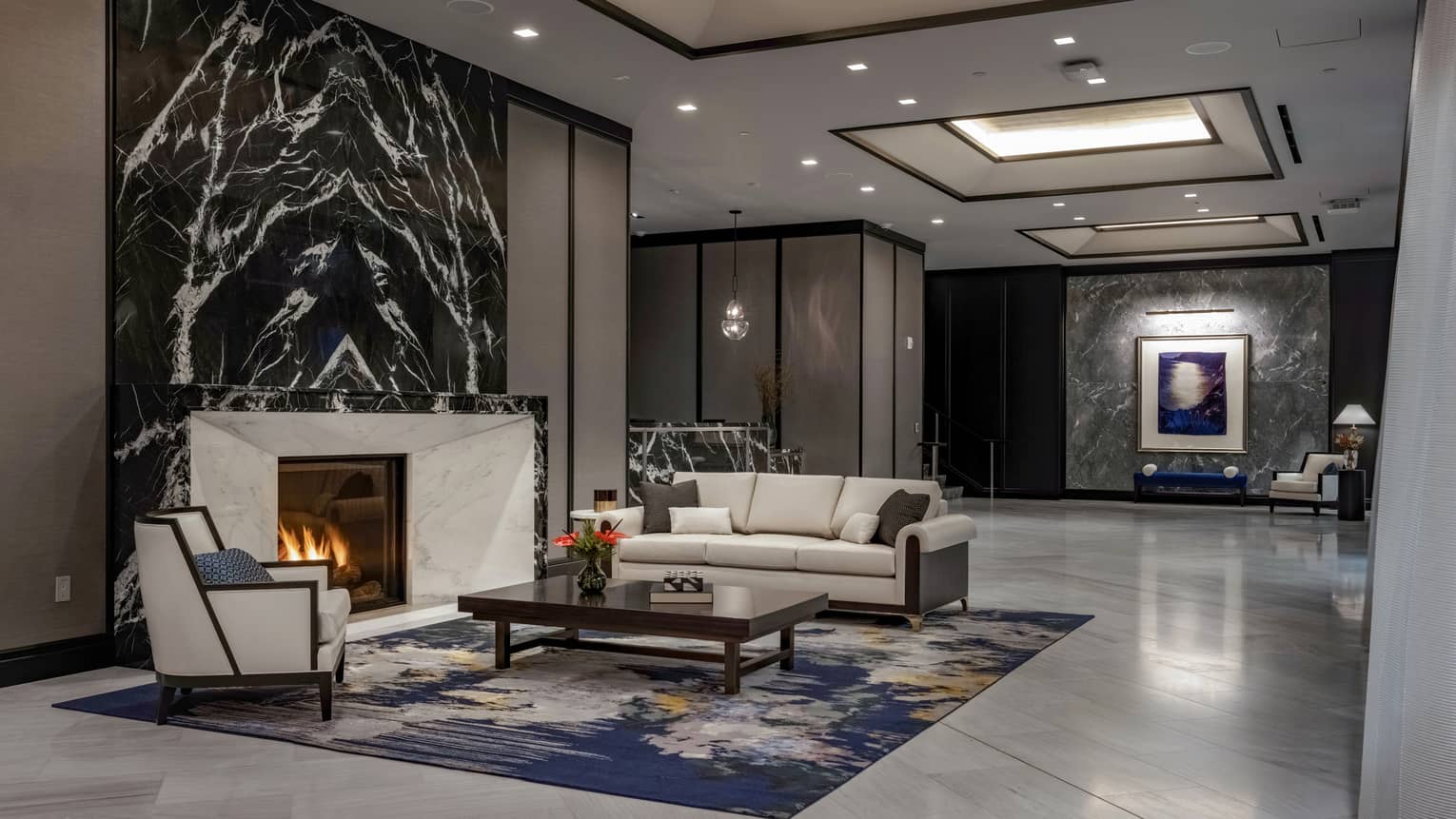 Lobby area with fireplace, couch and lounge chair.